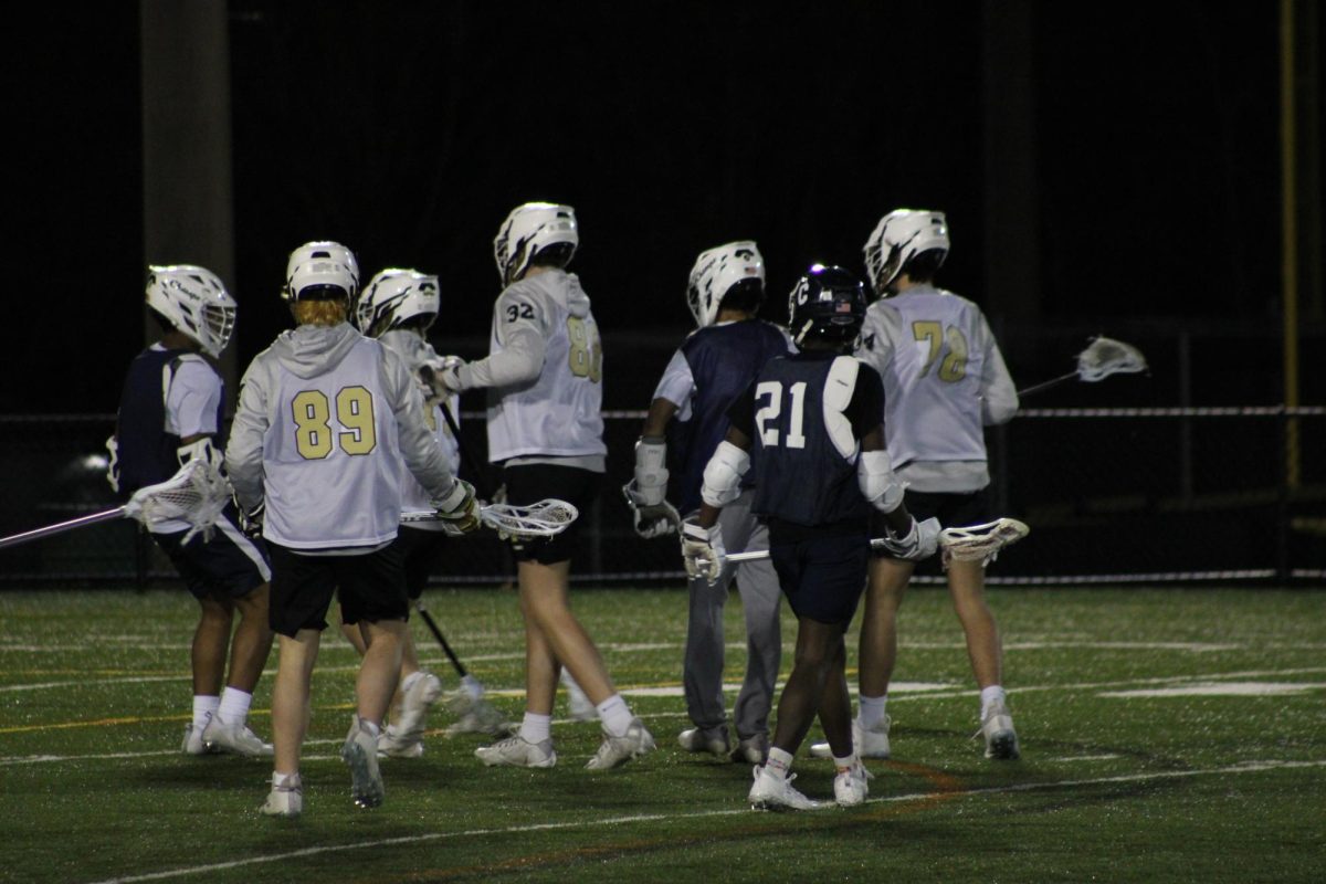 The boys lacrosse team is running onto the field to start their game. This led to their first win of the season against Westfield.