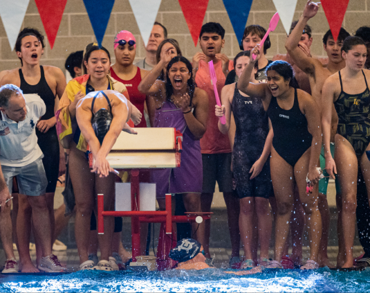Teammates cheering as a swimmer starts her race. 