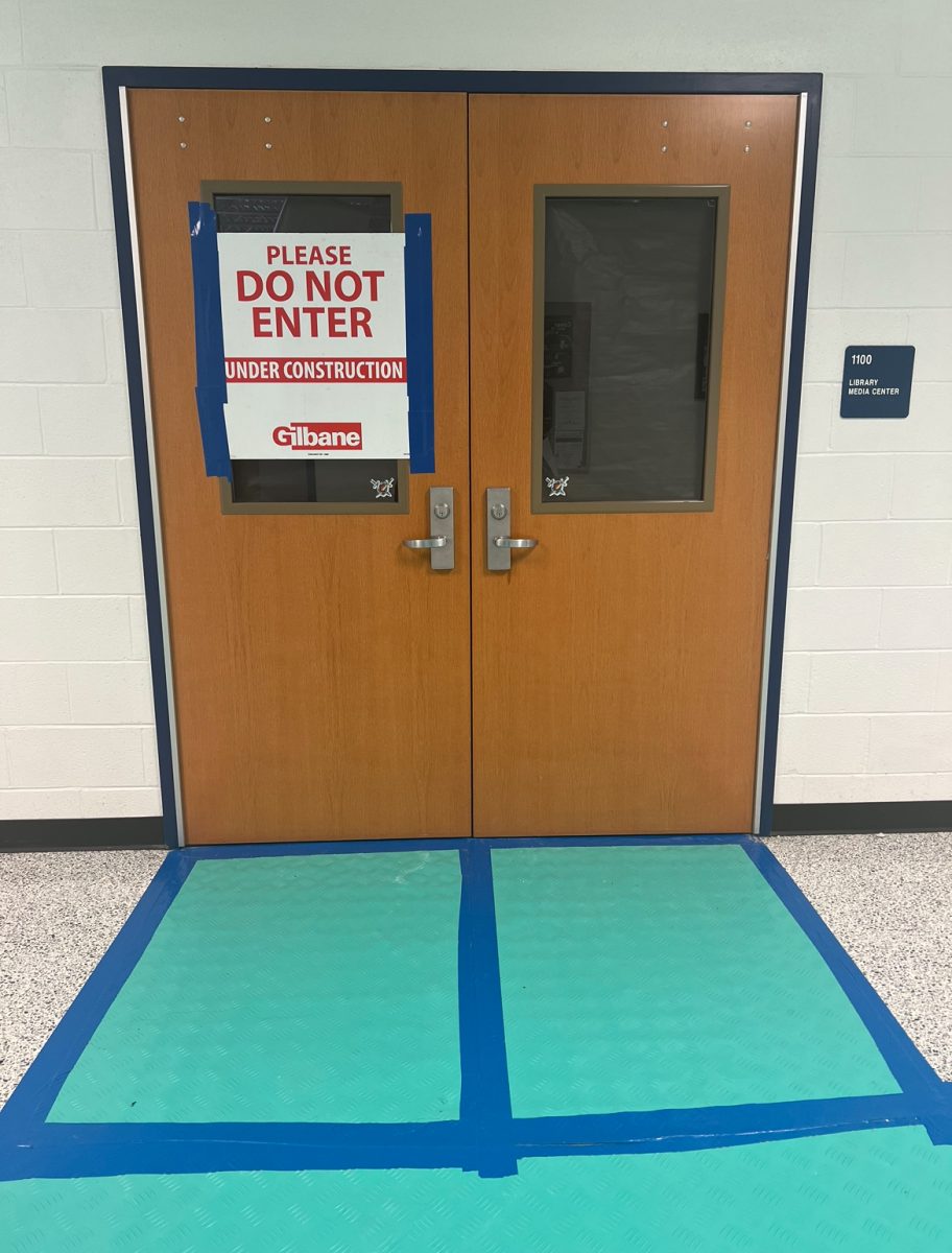 A sign posted on the entrance of the Library doors on March 15, 2024, by Gilbane informing students to not enter the Library. Gilbane has also laid out flooring protection to prevent damage to the tile in the main hallway/surrounding areas during construction.