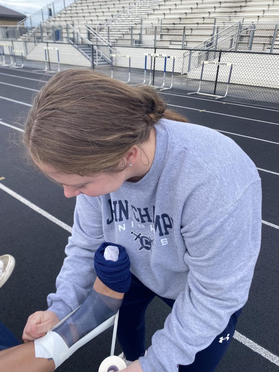 Image of John Champe athletic trainer, Sarah Charmo, treating an athlete.
