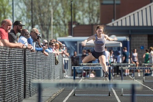 Sophia Hoopingarner jumping over hurdle during her race.