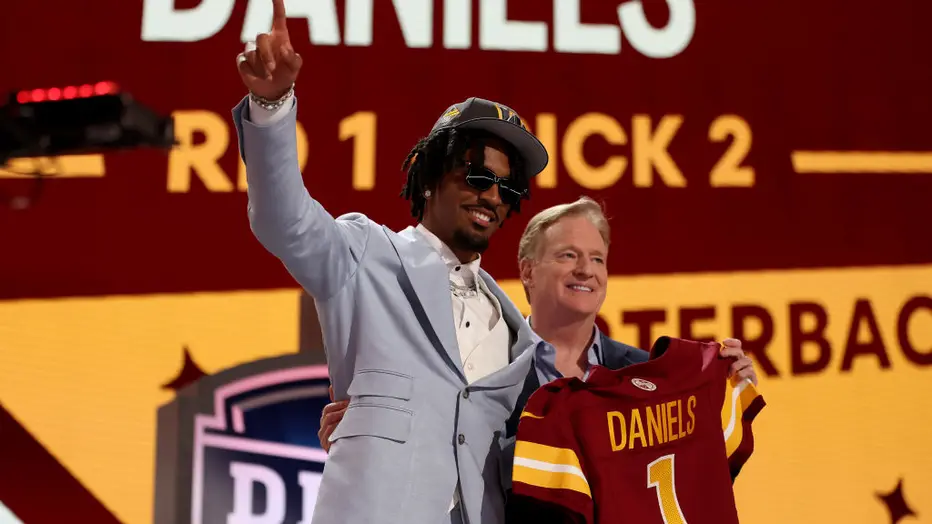 Picture of number two overall pick Jayden Daniels as he reaches the stage with NFL commissioner Roger Goodell (Photo by Gregory Shamus)