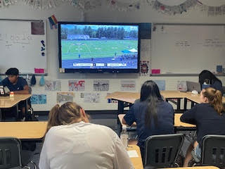 Students in Mrs. Mois Newspaper class watch the Girls Soccer Semi-Final game and also complete work