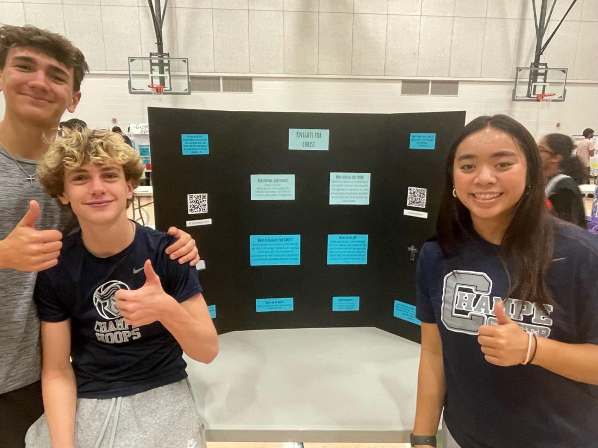 Jacob Dawson, Charlie Currier and Marella Batu show students their Knights For Christ poster in an effort to gain more members. The group prepared for the Club Fair by creating an Instagram account and bringing candy as a reward for those who join.