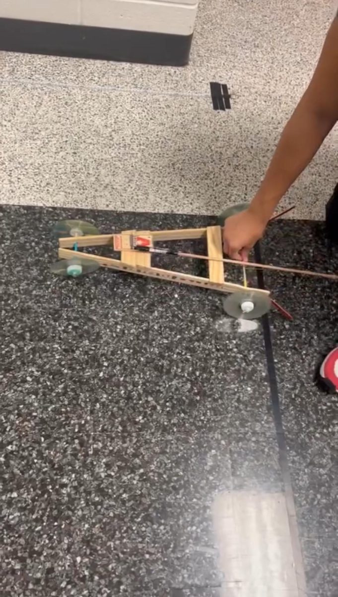 A student testing out their mousetrap car to record time and speed data. Most mousetrap cars had a common body as pictured above. 