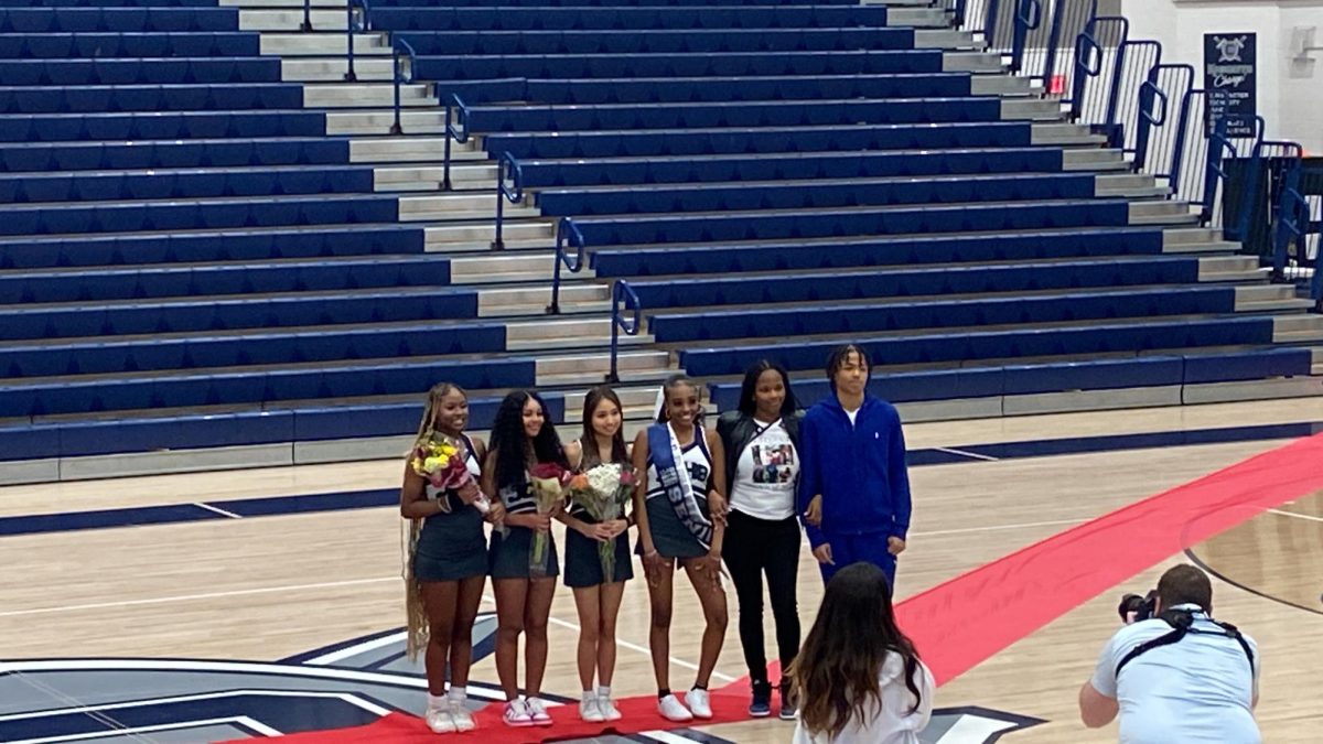 This photo was taken in the main gym during senior night for Varsity cheerleading and Varsity girls basketball. This picture is of Varsity cheerleader Tatyana Wilson being walked down the red carpet by her family and friends.